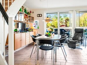 A modern kitchen with a dining area, large windows, and a staircase.