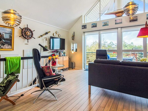 Een ruime woonkamer met een groot raam, een televisie en een eettafel.