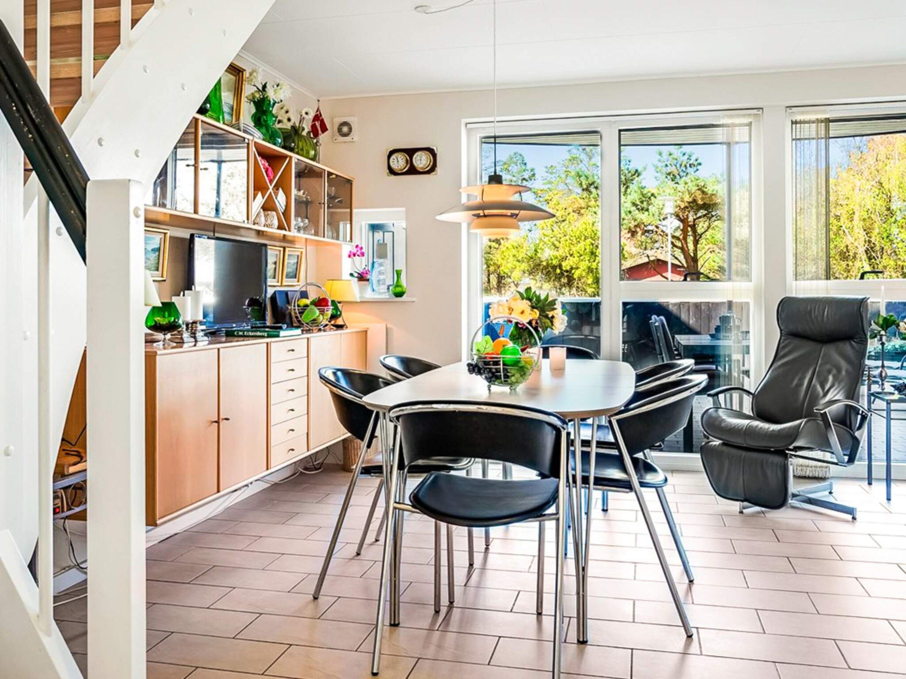 A modern kitchen with a dining area, large windows, and a staircase.