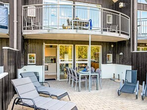 A two-story building with a balcony, outdoor seating area, and a visible kitchen.
