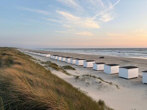 A row of white beachside cabins with a view of the ocean.