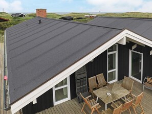 Um terraço com mesa e cadeiras, um espaço de varanda coberto e vista para a paisagem ao redor.