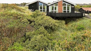 Un bâtiment moderne doté d’une terrasse, entouré d’une végétation luxuriante.