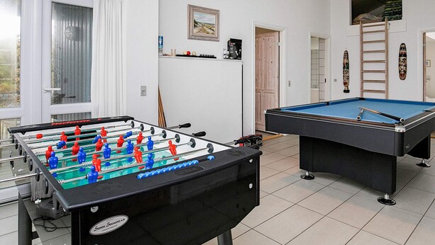 Une pièce avec une table de baby-foot, une table de billard et une fenêtre avec des rideaux.