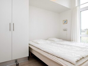 Une chambre à coucher comprenant un lit, une armoire, une fenêtre et un luminaire fixé au mur.