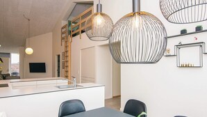 Moderni keittiö, jossa on keskeinen saareke, riippuvalaisimet ja portaikko, joka johtaa ylemmälle tasolle.