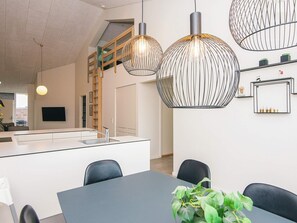 A modern kitchen with a central island, pendant lights, and a staircase leading to an upper level. - 5 Star Holiday Home in Ringkobing (Ringkobing)