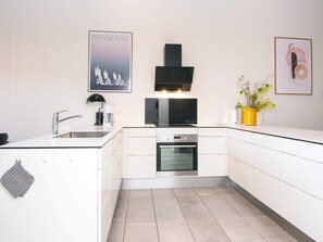 A modern kitchen with white cabinetry, a built-in oven, and a coffee maker. - 5 Star Holiday Home in Ringkobing (Ringkobing)