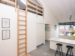 A modern kitchen with a central island, wooden ladder, and framed artwork on the walls.