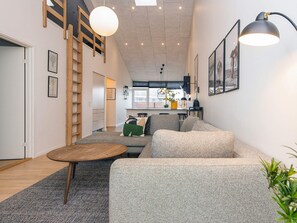 A modern living room with a sofa, a coffee table, and a staircase. - 5 Star Holiday Home in Ringkobing (Ringkobing)