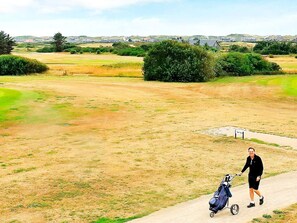 A person walking a stroller on a paved path in a rural area with fields and distant buildings. - 5 Star Holiday Home in Ringkobing (Ringkobing)