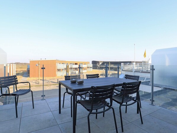 Une terrasse sur le toit, avec une table et des chaises, une vue sur les bâtiments et un drapeau.