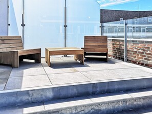 An outdoor seating area with benches and a table on a tiled patio. - 5 Star Holiday Home in Ringkobing (Ringkobing)