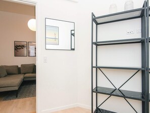 A modern living room with a sectional sofa, a black metal shelving unit, and a framed picture on the wall. - 5 Star Holiday Home in Ringkobing (Ringkobing)