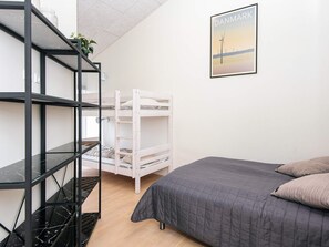 A bedroom with a bunk bed, a black metal shelf unit, a grey bedspread, and a framed picture of wind turbines on the wall. - 5 Star Holiday Home in Ringkobing (Ringkobing)