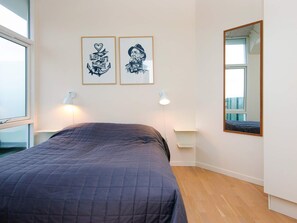 A bedroom with a bed, two wall-mounted lamps, and two framed pictures. - 5 Star Holiday Home in Ringkobing (Ringkobing)