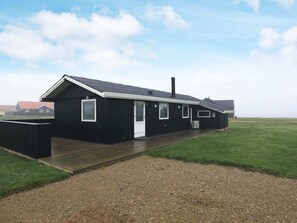 Een zwart gebouw met een witte deur, ramen en een schoorsteen.