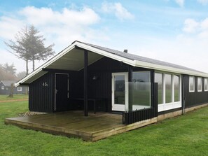 A modern building with a large glass door and a wooden deck. - 4 Star Holiday Home in Vinderup (Vinderup)