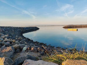 A calm waterfront with a rocky shoreline, calm water, and distant wind turbines. - 4 Star Holiday Home in Vinderup (Vinderup)