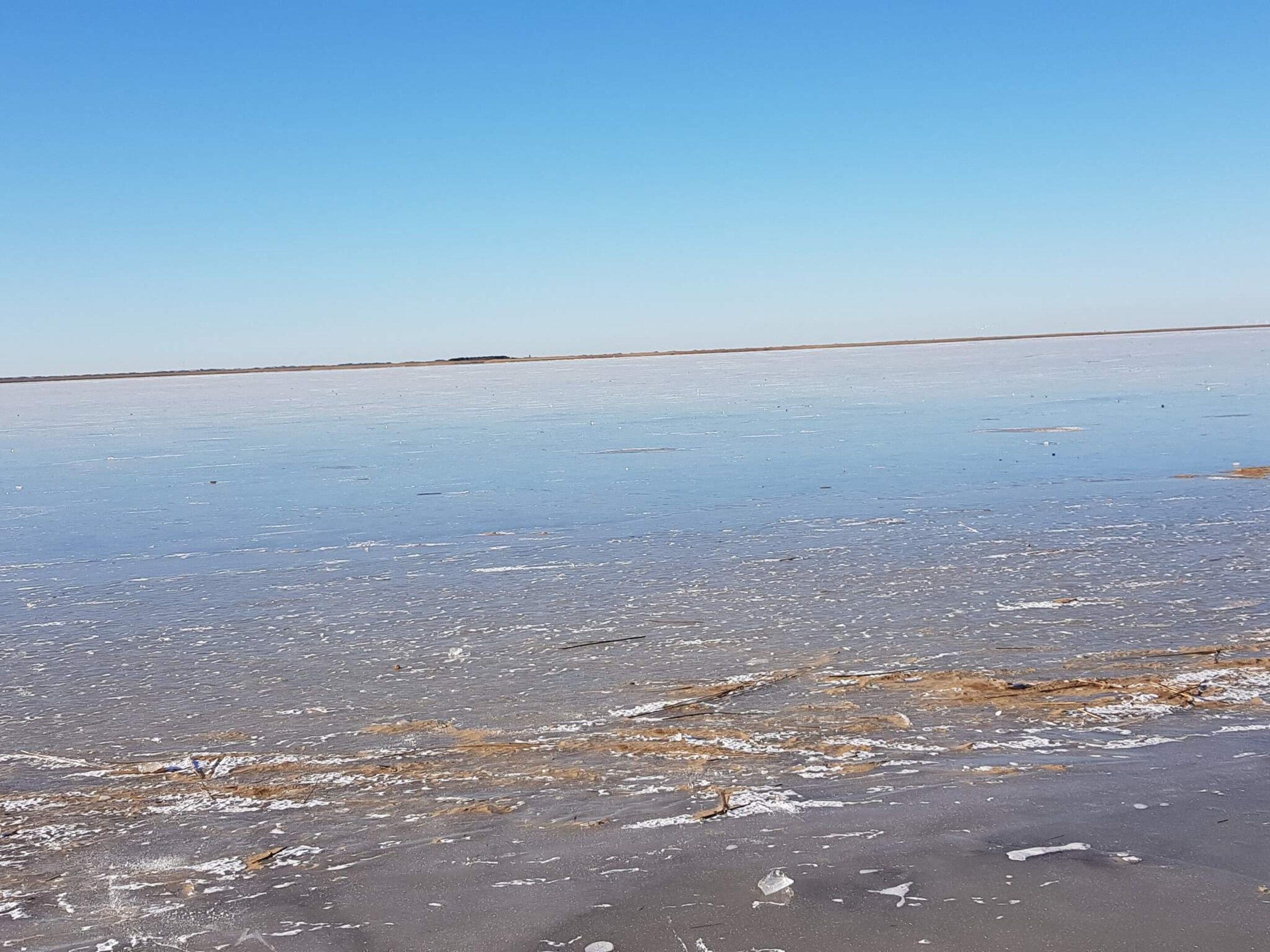 A flat, expansive salt flat with a clear sky.