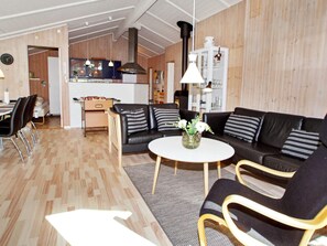 A modern living room with a black leather sofa, a round coffee table, and a dining area with a white table and chairs. - 7 Person Holiday Home in Hemmet (Hemmet)