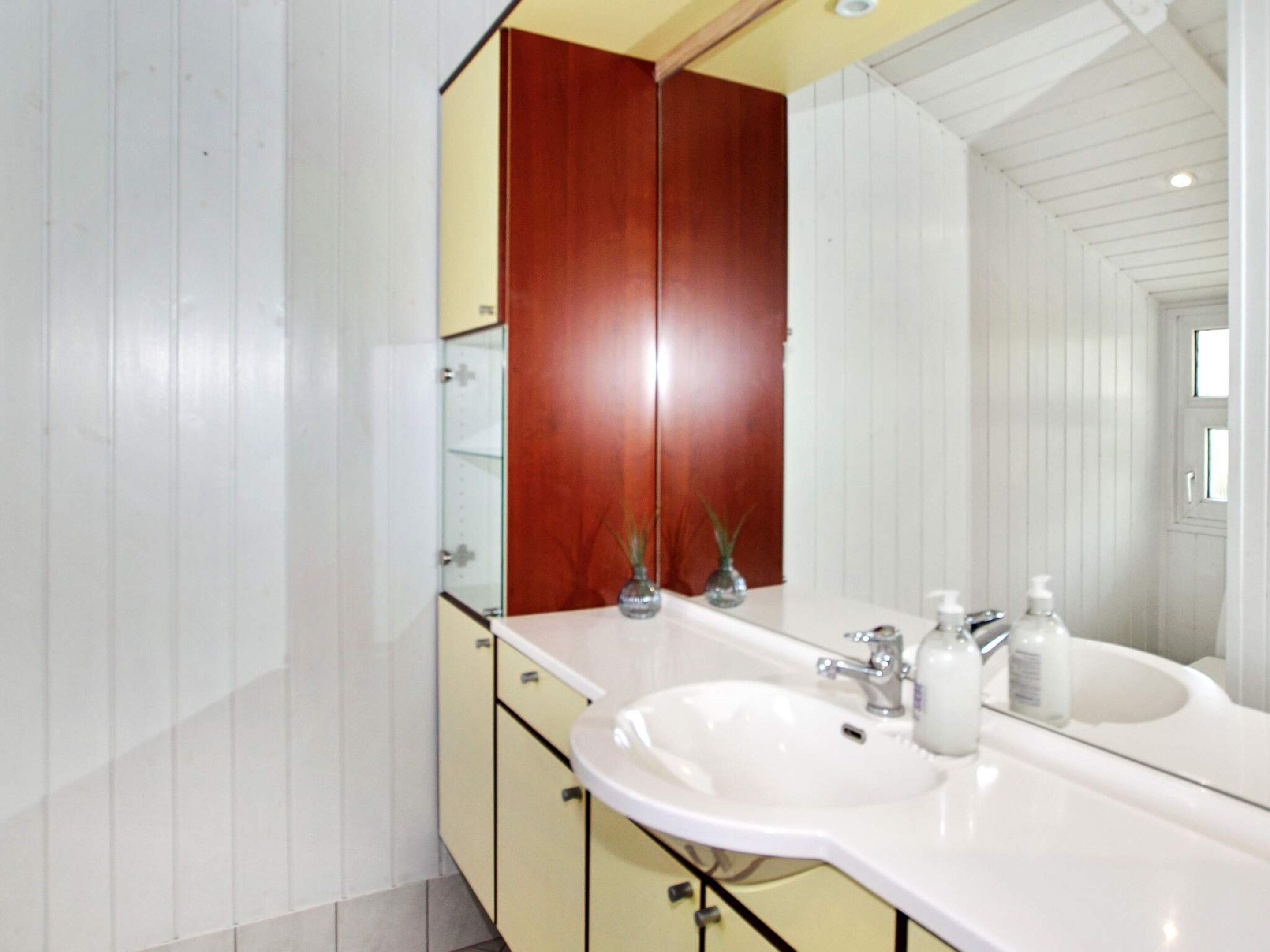 A bathroom with a double sink, wooden cabinets, and a large mirror.