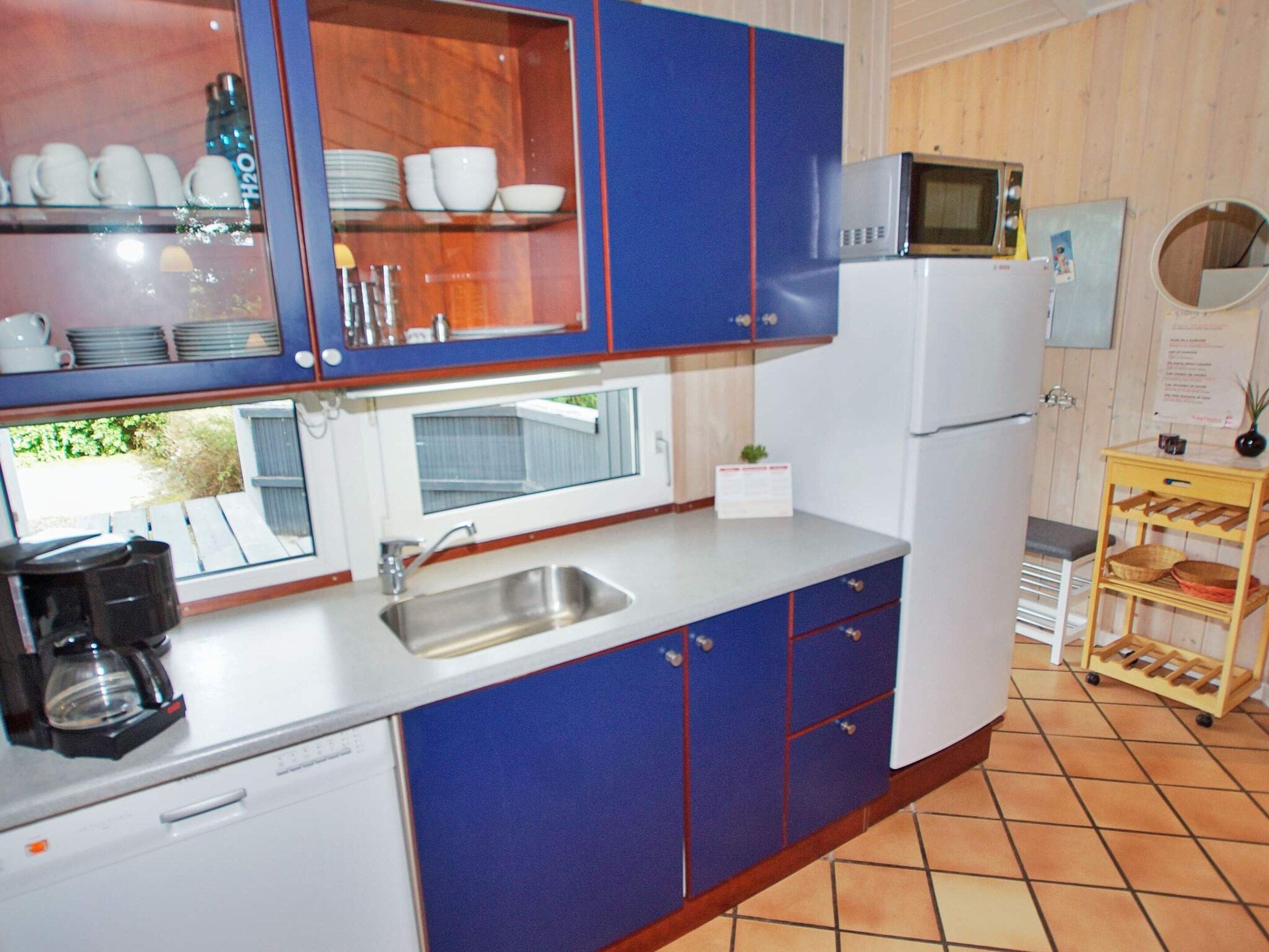A kitchen with blue cabinets, a white refrigerator, a microwave, and a coffee maker.