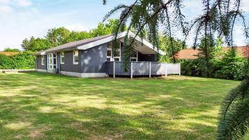 A single-story house with a fenced yard, surrounded by trees and a clear sky.