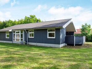 A single-story building with a dark blue exterior, white trim, and a grey roof. It features a large window on the front and a smaller window on the side. - 7 Person Holiday Home in Hemmet (Hemmet)