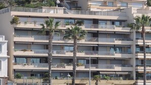 A multi-story building with balconies, palm trees, and a car parked in front. - Front de mer / 3 Pièces 91 m2 / 3ème Avec Ascenseur / Parking / 4 (Bandol)
