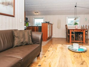 Ein gemütliches Wohnzimmer mit einem braunen Ledersofa, einem Holzespeisetisch und einer Küche im Hintergrund.