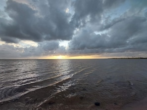 A beach with waves and a cloudy sky.