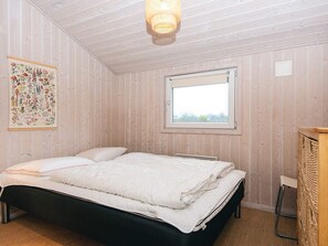 Une pièce avec un lit, une fenêtre et un luminaire fixé au mur.