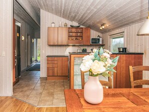 Een moderne keuken met houten kastjes, een magnetron en een eethoek met een tafel en stoelen.