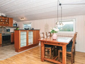 A kitchen with wooden cabinets, a dining table with chairs, and a window with a view.