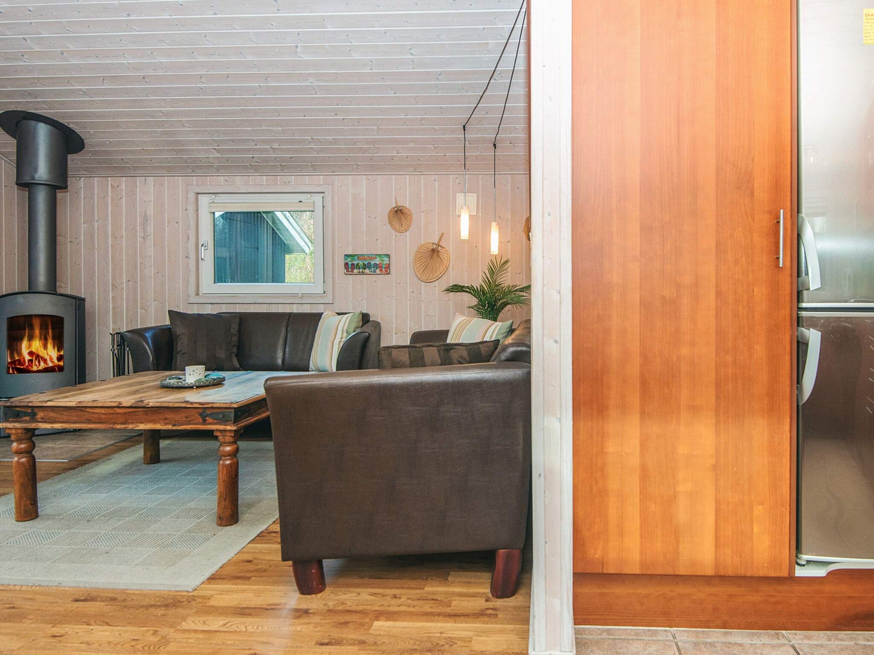 A cozy living room with a wood-burning stove, a sofa, a coffee table, and a refrigerator.