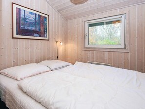 Een kamer met een bed, een raam en een schilderij aan de muur.