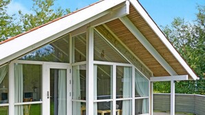 Una casa moderna con techo inclinado, amplios ventanales y un patio cubierto.