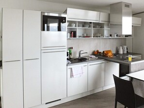 A modern kitchen with white cabinetry, a built-in microwave, and a coffee maker. - Holiday Home in Wendtorf (Wendtorf)