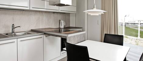 A modern kitchen with a built-in stove, a sink, and a dining area with a table and chairs.