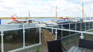 A waterfront restaurant with outdoor seating, a view of the water, and boats in the background. - Holiday Home in Wendtorf (Wendtorf)