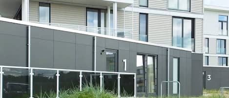 Un immeuble résidentiel à plusieurs étages, doté de balcons, de grandes fenêtres et d’une façade plane.