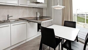 A modern kitchen with a built-in stove, a sink, and a dining area with a table and chairs. - Holiday Home in Wendtorf (Wendtorf)