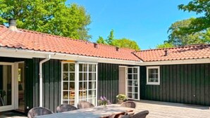 Une terrasse couverte avec une table et des chaises, une porte et une fenêtre.
