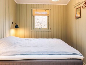 Una habitación con cama, ventana con vistas, lámpara de pared y espejo.