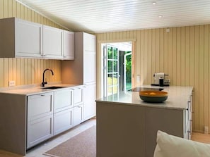 Cocina moderna con armarios blancos, una isla central y vistas al exterior.