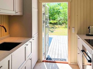 A kitchen with white cabinets, a wooden countertop, and a door leading to an outdoor deck. - 8 Person Holiday Home in Vaeggerlose (Vaeggerlose)