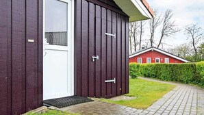 A modern building with a dark exterior, a white door, and a small window. - Holiday Home in GrÃ¶mmitz (Groemitz)