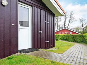 A modern building with a dark exterior, a white door, and a small window. - Holiday Home in GrÃ¶mmitz (Groemitz)