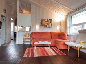 A modern living room with a sectional sofa, a round coffee table, and a wooden floor. - Holiday Home in GrÃ¶mmitz (Groemitz)
